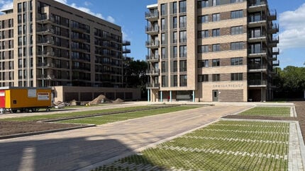 Twee moderne appartementengebouwen met meerdere verdiepingen, grote ramen en balkons, omgeven door een nieuw aangelegde bestrating en groenstroken.
