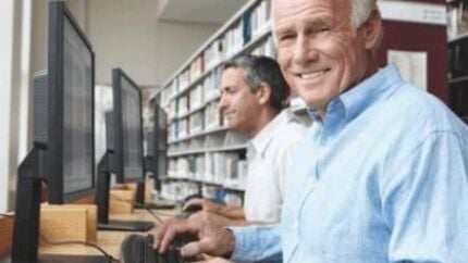 Persoon werkt op computer in bibliotheekachtige omgeving